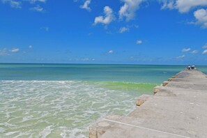 A concrete pier extending into a calm sea with clear skies.