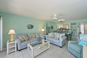 A living room with two sofas, a coffee table, and a dining area with a table and chairs. - Runaway Bay 128 - Beach, Pool, gym and bay (Bradenton Beach)
