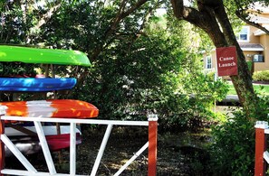 A canoe launch area with a sign, surrounded by trees and a fence. - Runaway Bay 128 - Beach, Pool, gym and bay (Bradenton Beach)