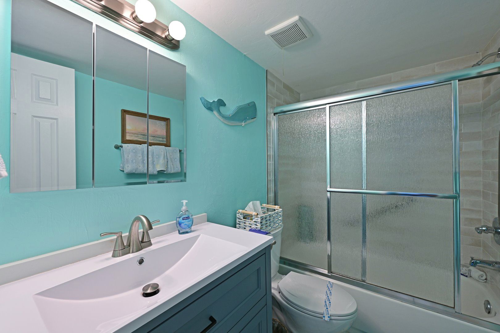 Un bagno con uno specchio grande, un lavandino, un water e un box doccia.