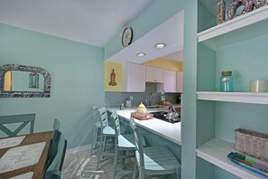 A kitchen with white cabinets, a sink, and a breakfast bar. There are chairs and a table with a menu. - Runaway Bay 128 - Beach, Pool, gym and bay (Bradenton Beach)