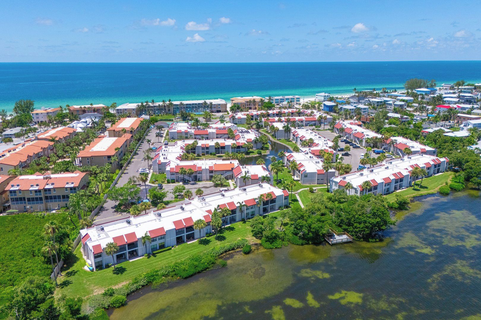 Un complejo turístico costero con varias edificaciones, un puerto deportivo y vista al océano.