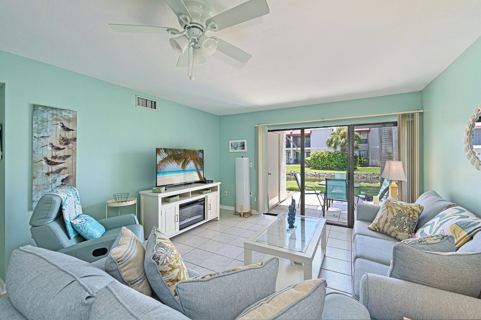 A living room with a television, sofas, a coffee table, and a ceiling fan.