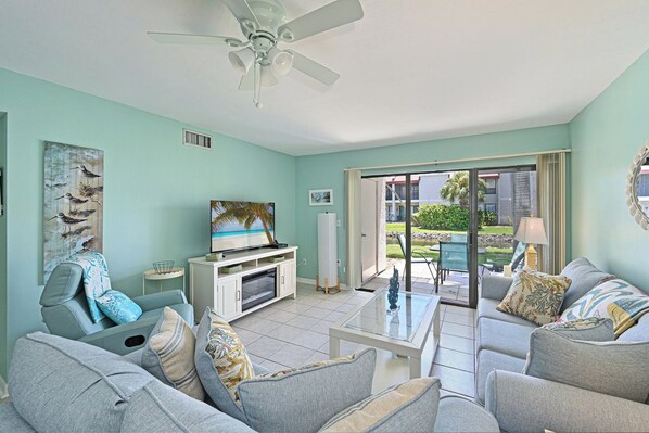 A living room with a television, sofas, a coffee table, and a ceiling fan.