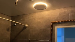 A bathroom with a shower, toilet, sink, and a mirror with a decorative frame. - The Broadway Inn (Los Angeles)