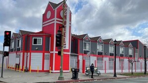 A motel with a distinctive red and white facade, multiple garage doors, and a prominent clock tower. - The Broadway Inn (Los Angeles)
