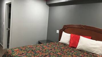 A bedroom with a bed, a nightstand, a door, and a wall with a red trim.