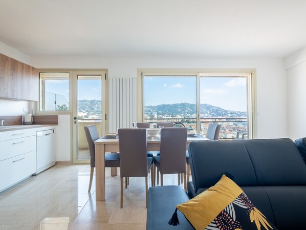 Un appartement moderne comprenant un coin repas, une cuisine et un canapé offrant une vue sur la ville.