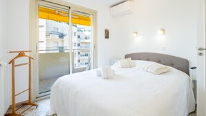 A bedroom with a bed, a wooden hanger, a radiator, and a view of balconies through a door. - 3-Br. apartment near downtown Cannes. Sea view, parking. (Cannes)