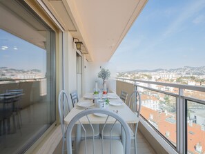 Un balcon avec une table dressée pour deux personnes, offrant une vue sur le paysage urbain.