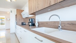 A modern kitchen with wooden cabinets, a white countertop, a sink, and a coffee maker. - 3-Br. apartment near downtown Cannes. Sea view, parking. (Cannes)