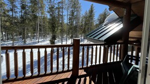 Una terraza de madera con barandilla que da a un bosque nevado.