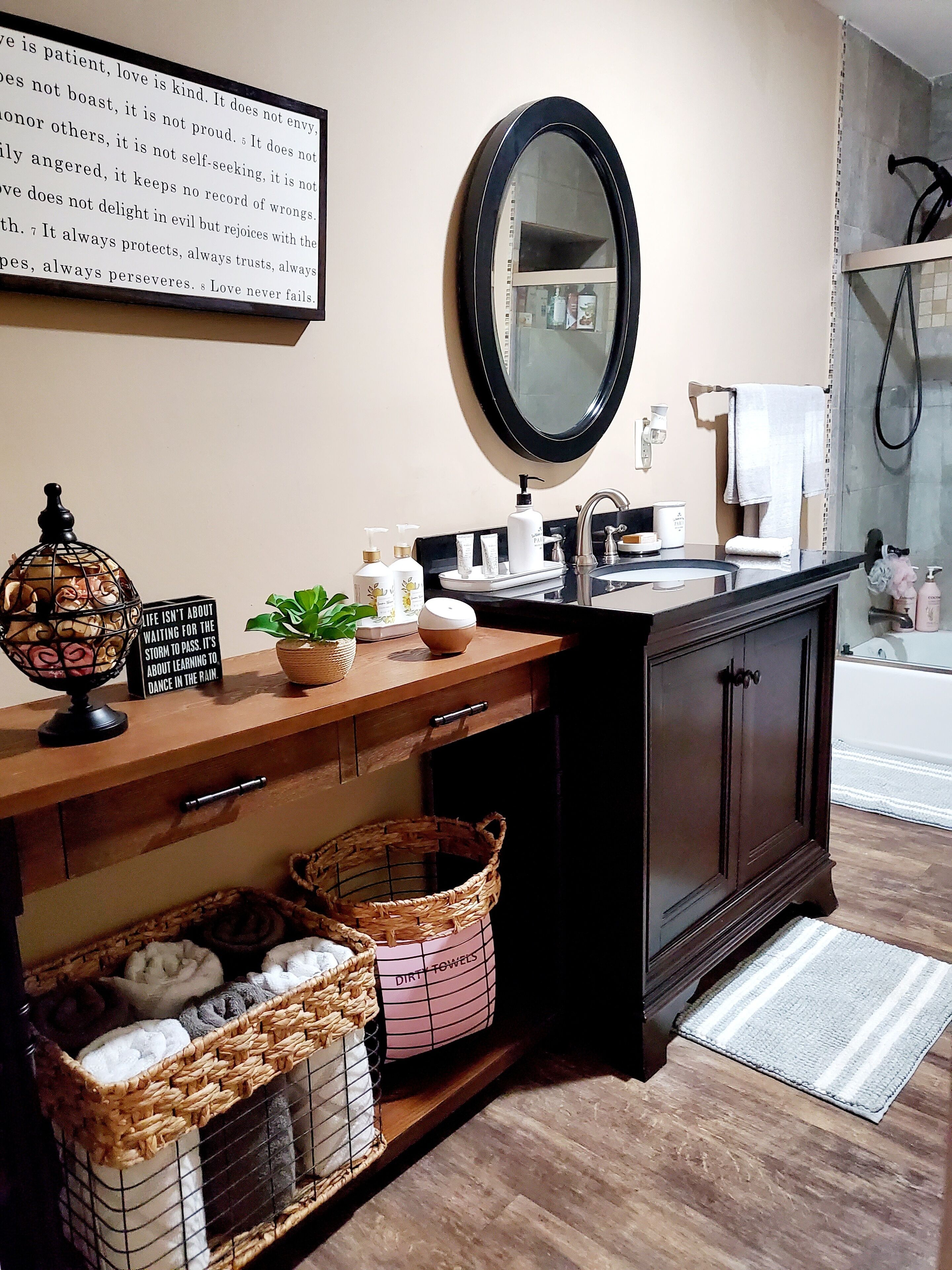 A bathroom with a wooden vanity, a large mirror, a sink, and a shower area.