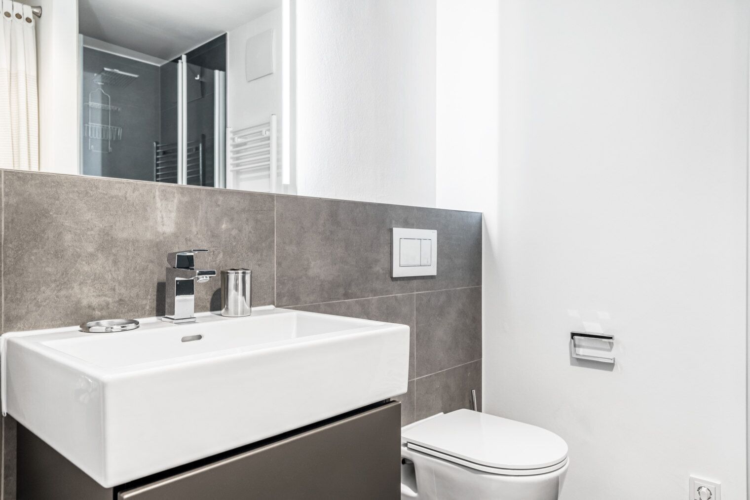 A modern bathroom with a white sink, a toilet, and a shower area.