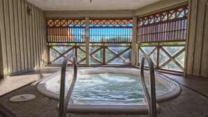 A hot tub with a view of a natural landscape through a wooden lattice window.