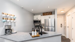 A modern kitchen with a central island, stainless steel appliances, and a coffee maker.