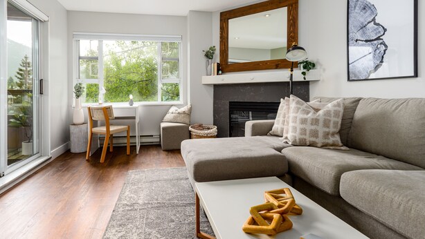 A modern living room with a sofa, a coffee table, a fireplace, and a dining area with a chair and table.