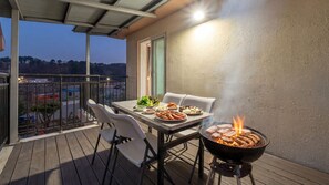 An outdoor patio with a grill, seating, and a view of the surrounding area.