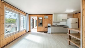 A modern kitchen with wooden walls, a large window, and a view of the outdoors.