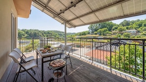 A balcony with a grill, dining table, chairs, and a view of a green landscape. - Samcheok Bongsuni-unni Pension (Samcheok)