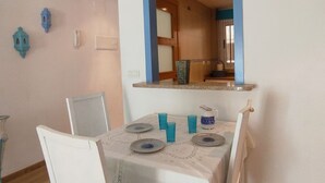 Un comedor con una mesa preparada para cuatro, un espejo sobre la mesa y faroles azules decorativos en la pared.