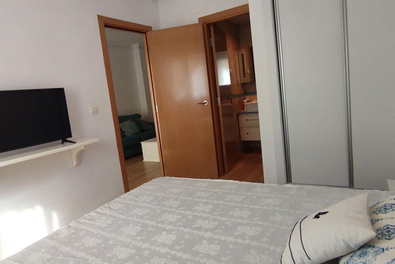 Ein Schlafzimmer mit einem Bett, einem Fernseher auf einem Regal, einem Kleiderschrank und einer Tür zu einem Badezimmer.