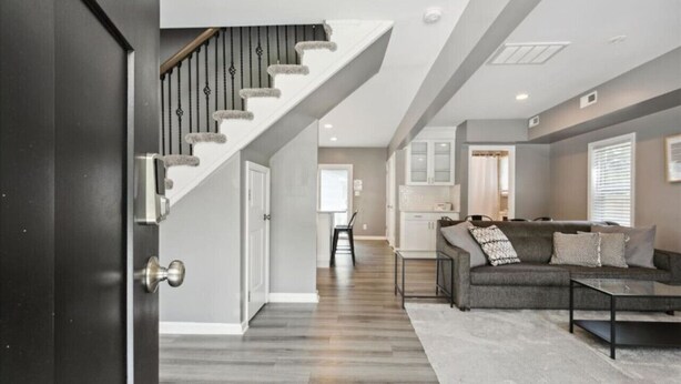 A modern living room with a gray sofa, a coffee table, and a staircase with a railing. - Monthly pet-friendly, <5 min walk to beach (Hampton)