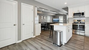 A modern kitchen with white cabinetry, a stainless steel oven, and a microwave. - Monthly pet-friendly, <5 min walk to beach (Hampton)