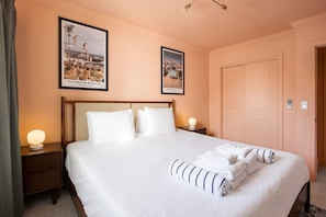 A hotel room with a large bed, two nightstands, a wooden headboard, and two framed pictures on the wall.