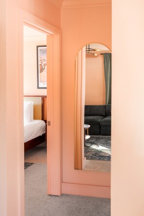 Une chambre à coucher avec un lit, un miroir, un canapé et un tableau encadré accroché au mur.