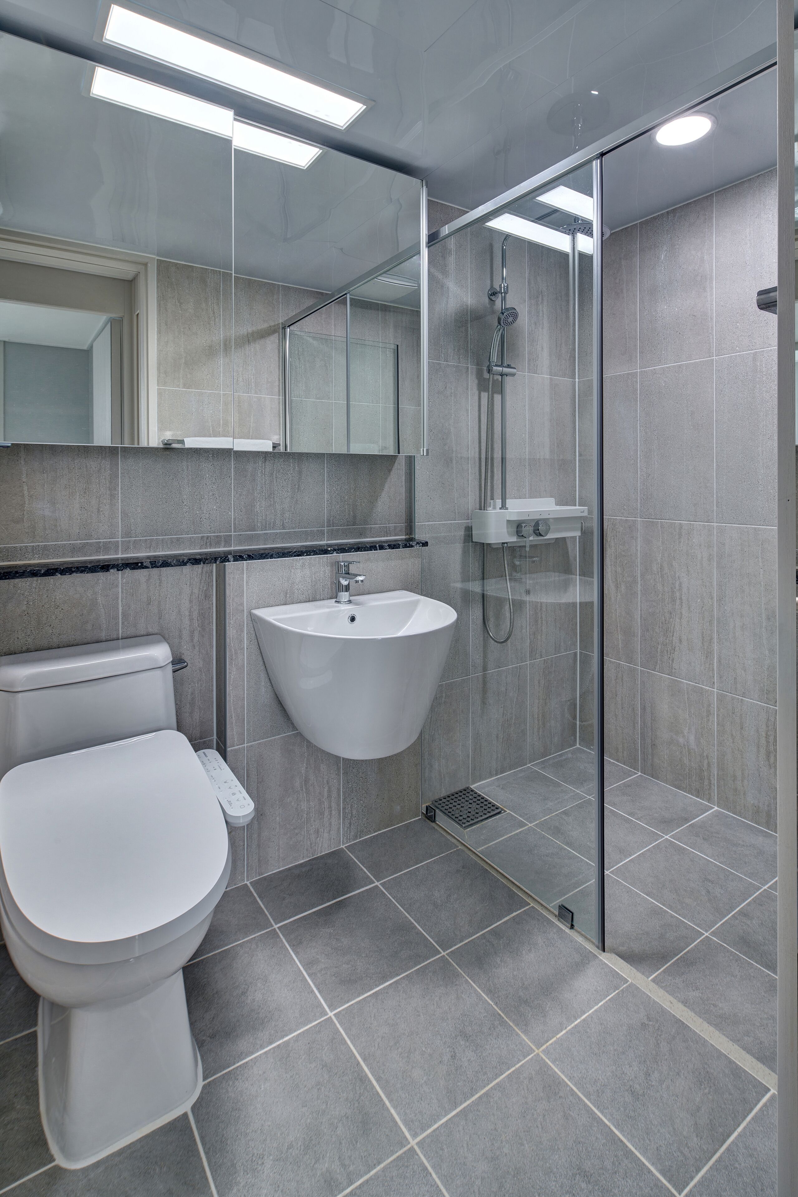 A modern bathroom with a toilet, sink, and glass-enclosed shower.