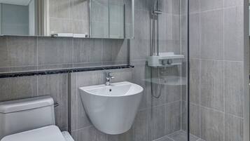 A modern bathroom with a toilet, sink, and glass-enclosed shower.