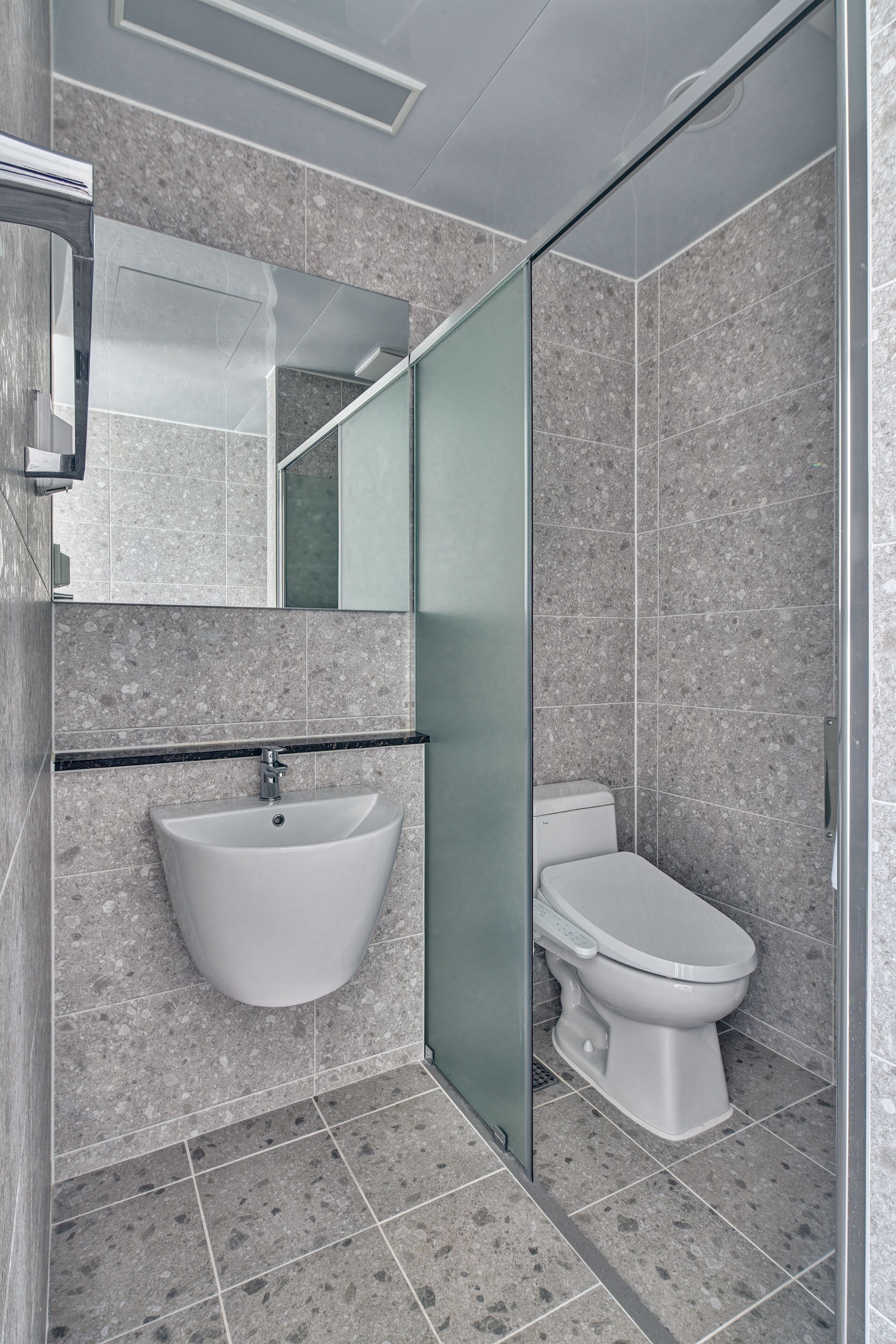 A modern bathroom with a glass shower enclosure, a white sink, and a toilet.