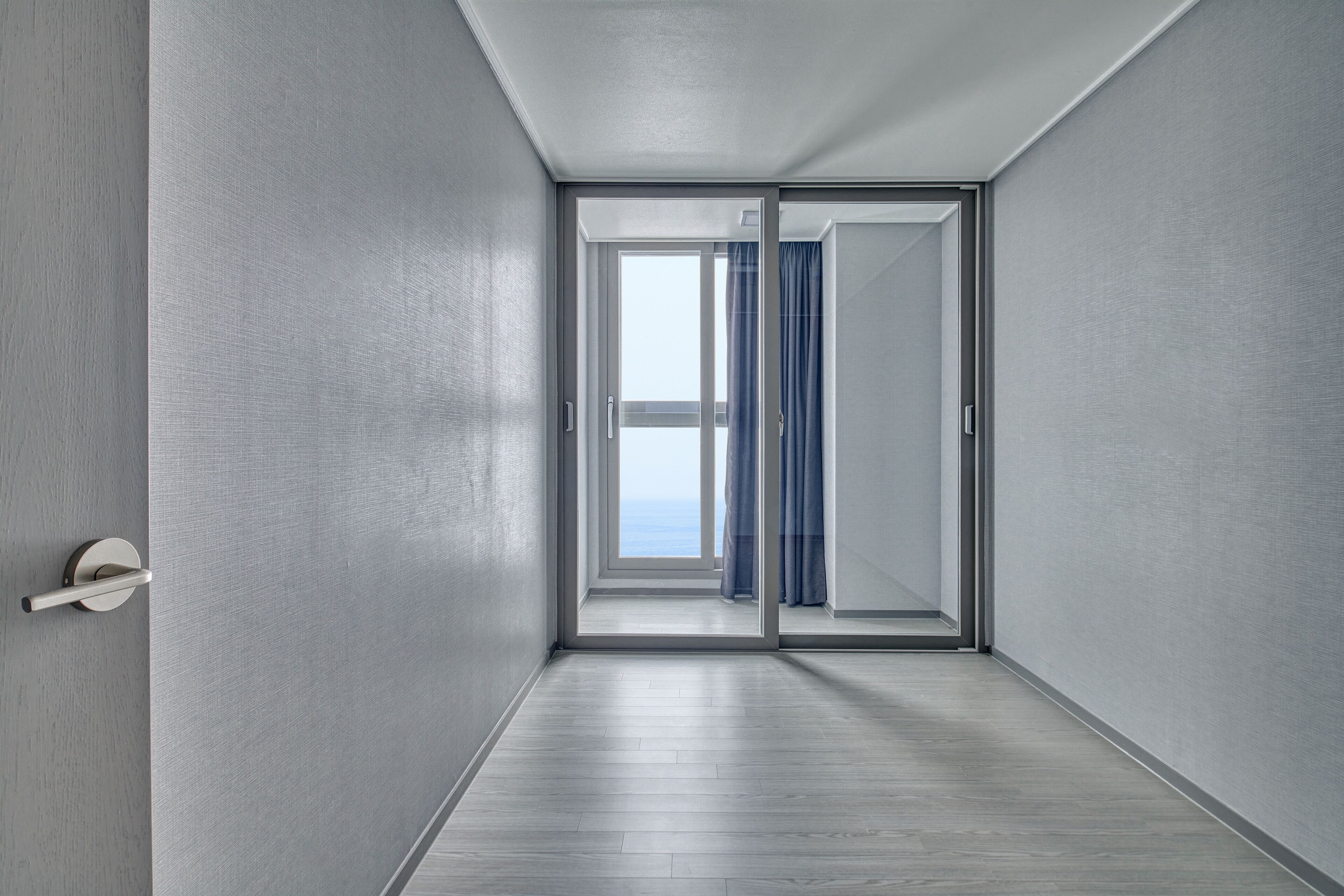 A modern hallway with a sliding glass door leading to a balcony with a view.