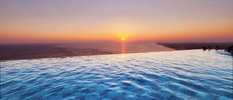 Ein Infinity-Pool mit Blick auf den Sonnenuntergang über dem Meer.