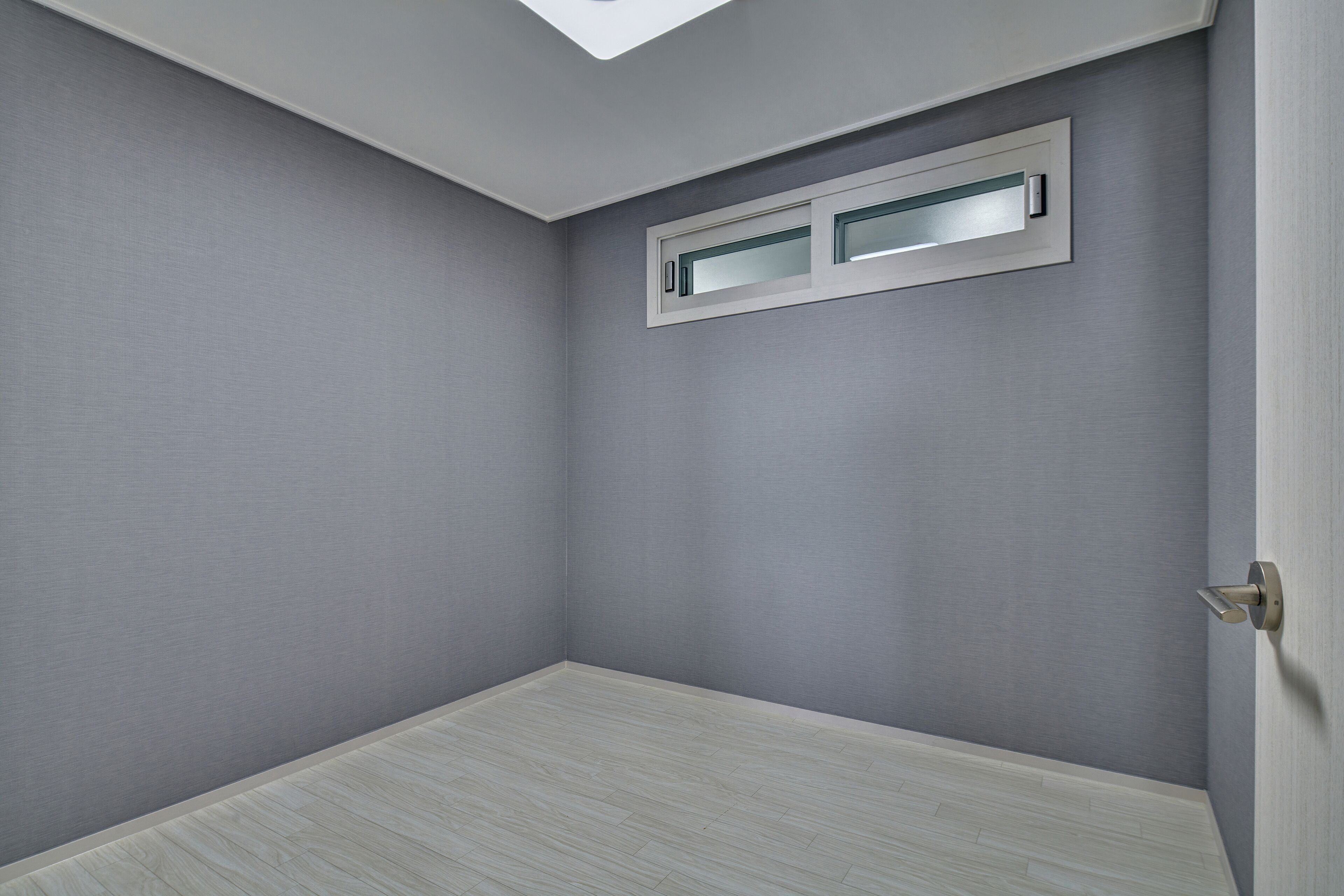 Una habitación con techo inclinado, una ventana con vistas y una puerta.