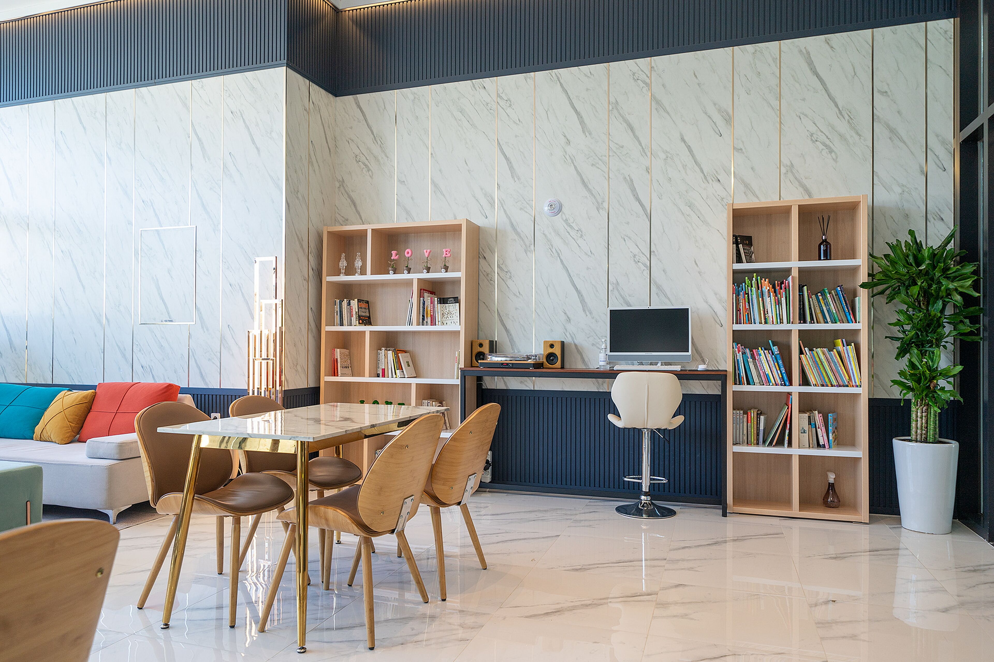 A modern living room with a dining area, bookshelves, a sofa, and a coffee table.