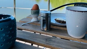 Una mesa de madera con una taza de metal, un recipiente de metal y una taza de cerámica.
