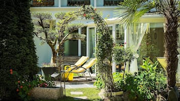 Een verzorgde tuin met diverse planten en een zitgedeelte met gele stoelen.