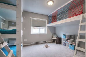 A bunk bed room with a window, storage cabinets, and a ladder.