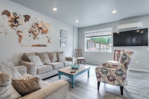 A living room with a world map, a television, and a window with a view. - Large Groups Near Glacier w/ Hot Tub & Game Room (Juneau)