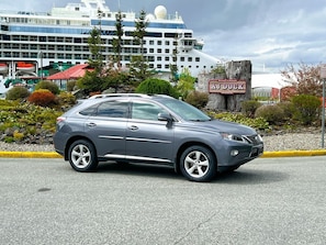 A gray SUV parked in front of a cruise ship dock.