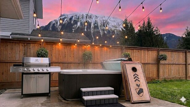 Un patio trasero con una parrilla, un jacuzzi y una valla de madera.