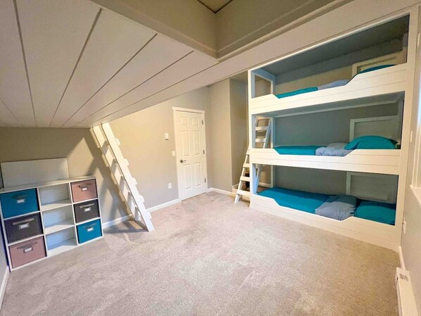 Una habitación con literas, una escalera y espacios de almacenamiento.