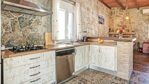 Eine Küche mit Steinwand, Holzboden, Edelstahlgeräten und Fliesenboden.