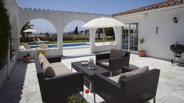 Eine Terrasse mit Gartenmöbeln, einem Grill und einem Pool.