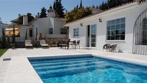 Ein Swimmingpool mit klarem, blauem Wasser, umgeben von einer weißen Terrasse mit Gartenmöbeln.