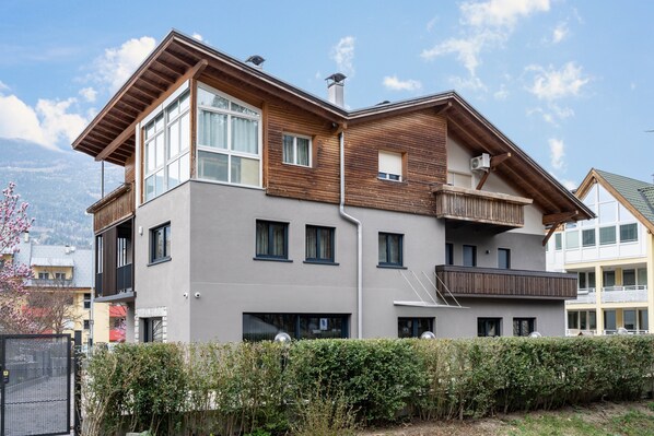 Un immeuble moderne à plusieurs étages, doté de balcons, de grandes fenêtres et d’une façade en bois.