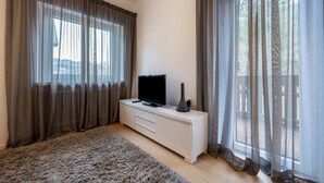 A modern bedroom with a large window, a flat-screen TV on a white dresser, and a fluffy rug on the floor. - Apartment 'Plose 35' in strategic location with Mountain View, Balcony & Wi-Fi (Bressanone)