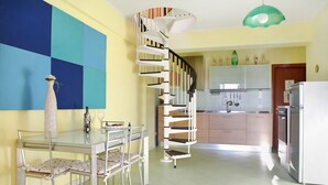 A modern kitchen with a spiral staircase, a dining table with chairs, and a refrigerator. - Sicily new apartment next sea with two bedrooms (Acireale)